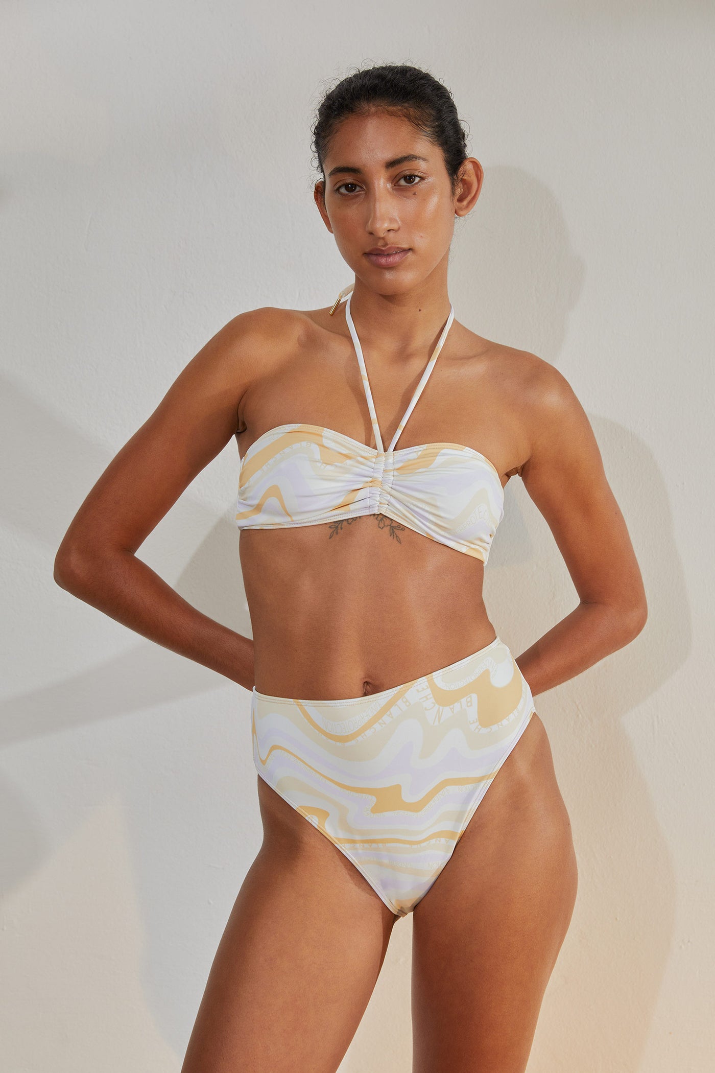 Young brown skinned female model with black pulled back hair seen from the front, wearing Brigitte Bikini Bandeau and Brigitte Bikini Briefs.